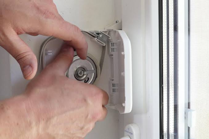 Technicien accédant au mécanisme d'enroulement par la trappe du caisson